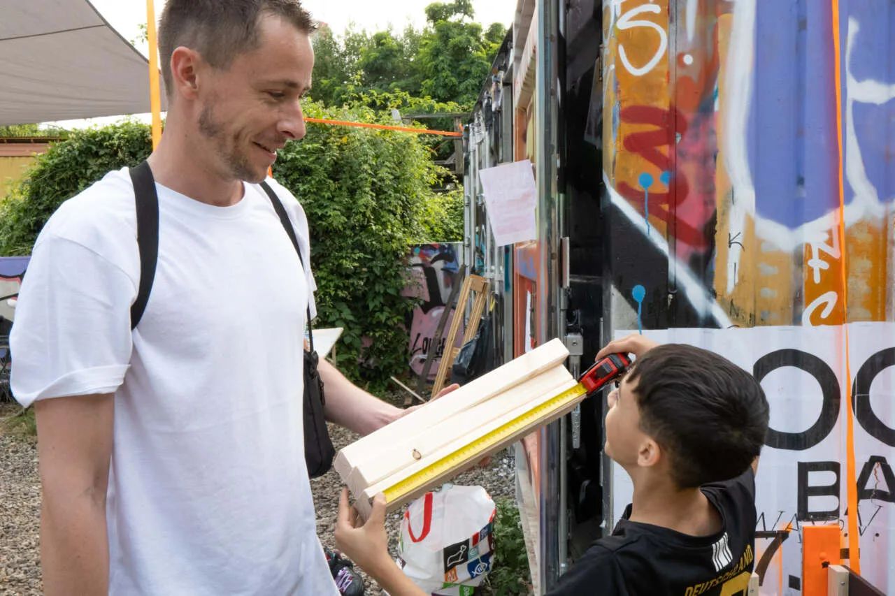 DogShitSpot — Mann und Kind beim Messen, Bauwoche